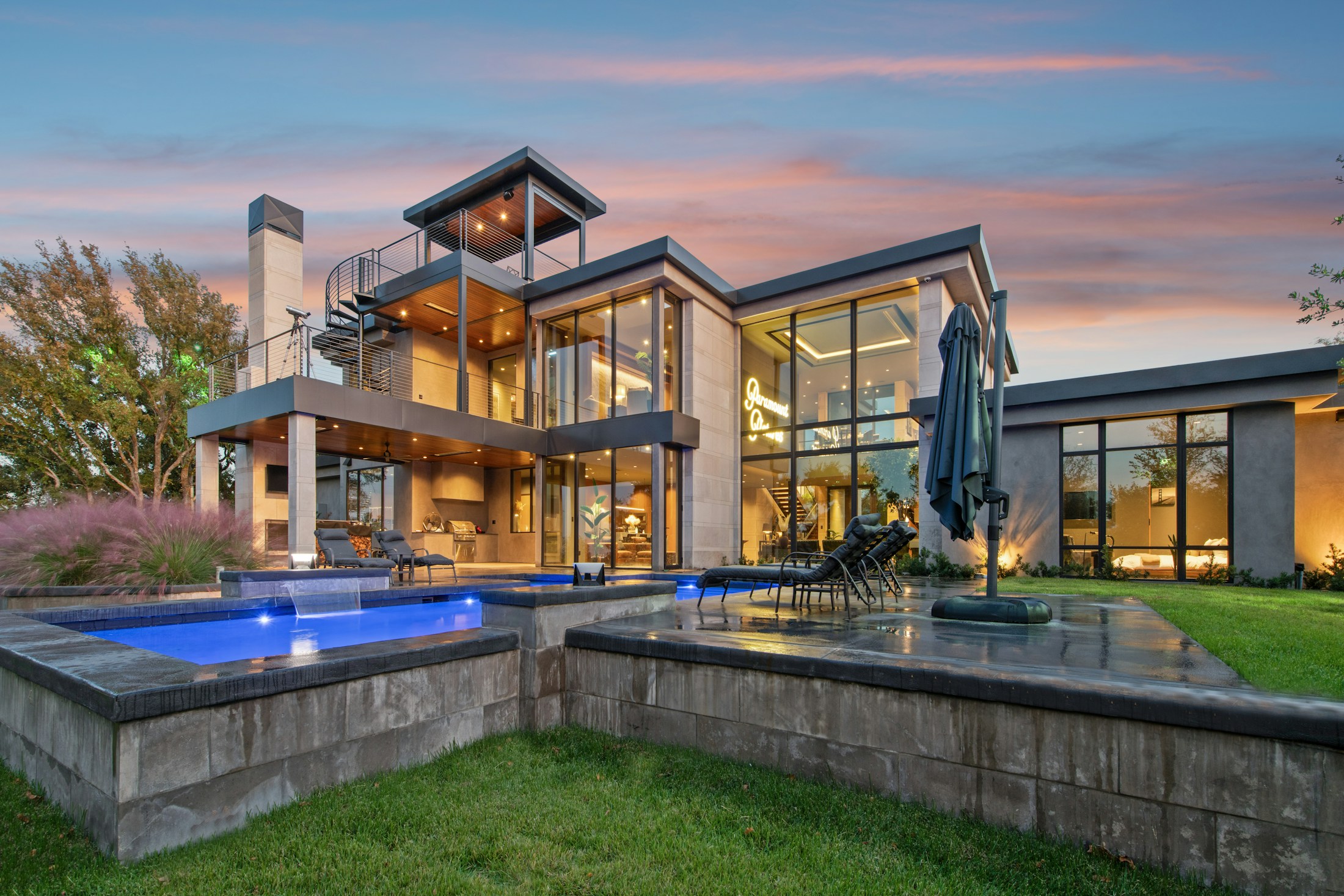 Contemporary home with terraces and illuminated pools at twilight